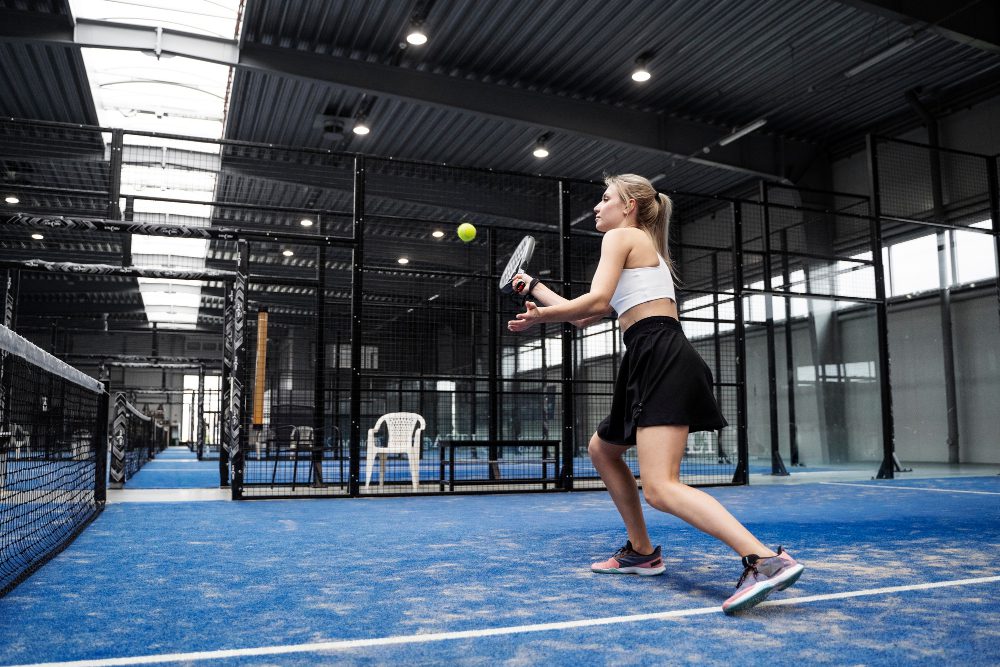Full shot fit woman playing paddle tennis