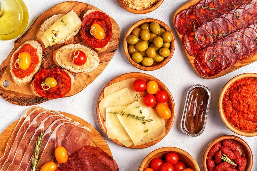 slices jamon chorizo sausage bowls with olives tomatoes anchovies mashed chickpeas cheese