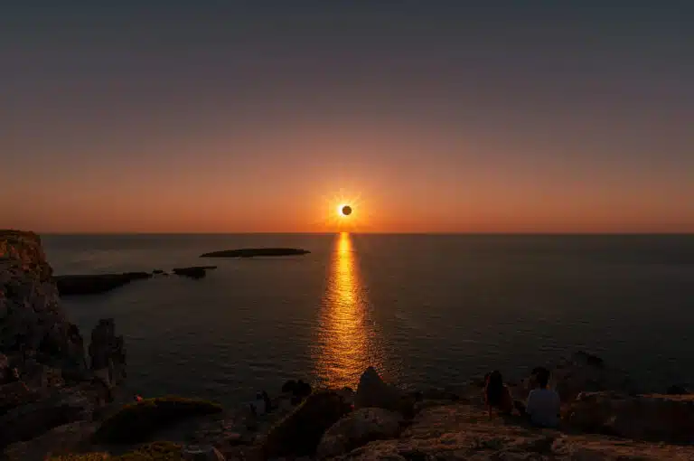 people watching a total solar eclipse at sunset from the rocky c